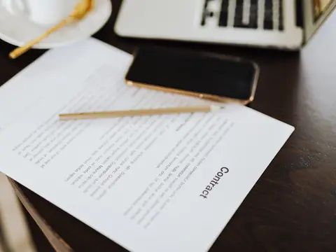 A contract, a phone and a laptop on a desk