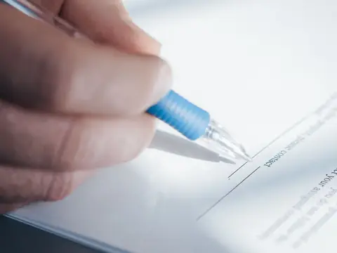A hand holding a pen while signing a document