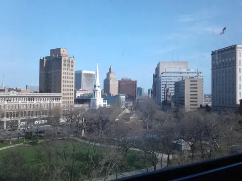 Downtown Newark towers above the trees of Military Park on a sunny day