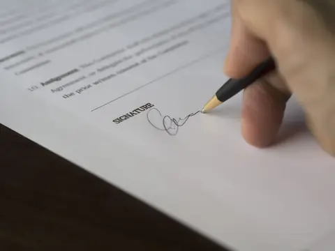 A hand signing a contract with a pen