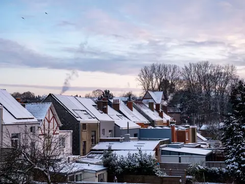 Snow on rooftops across a neighborhood at dusk