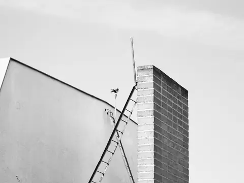 A ladder against a wall beside a brick chimney