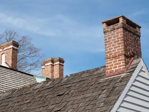 Brick chimneys rising from a worn shingle roof