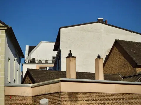 Chimneys and a flat roof parapet against a deep blue sky