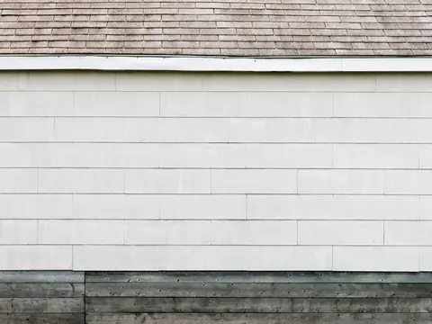 A shingled roof edge over white siding