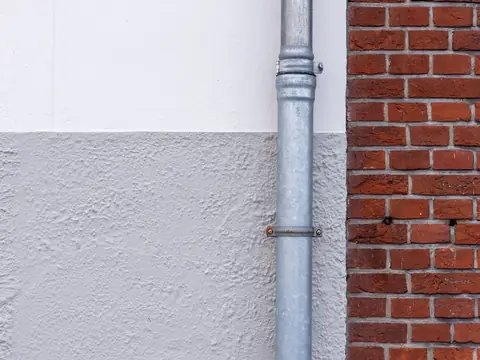 A metal leader running down beside a brick wall