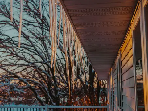 Icicles hanging from a roof edge at sunset