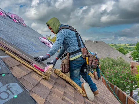 A roofer laying new shingles over underlayment
