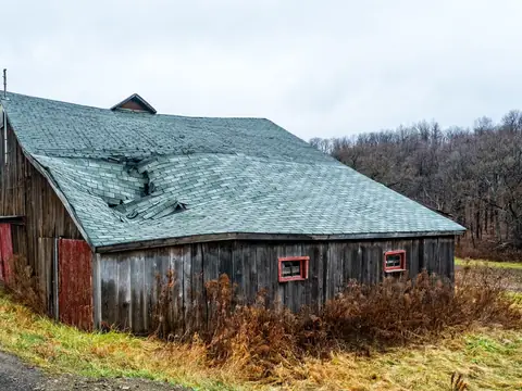 An old barn roof with worn, buckled shingles