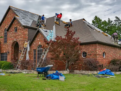 A roofing crew re-covering the roof of a brick house