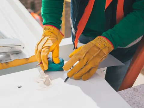 Gloved hands marking a metal panel on a roof