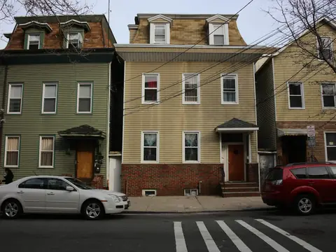 Two-family houses with mansard top floors on a Newark street